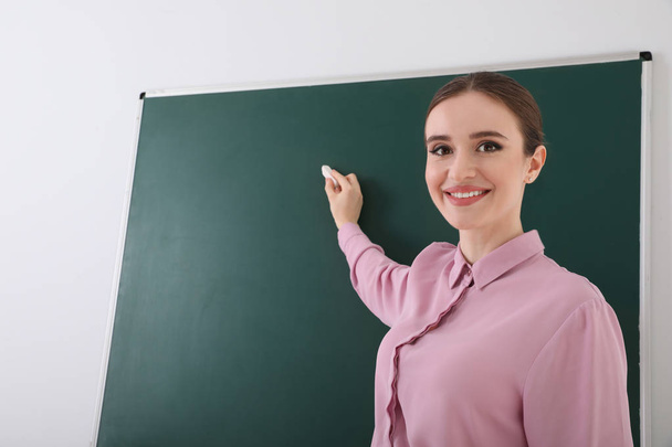 Portrait of young female teacher in classroom - Фото, изображение