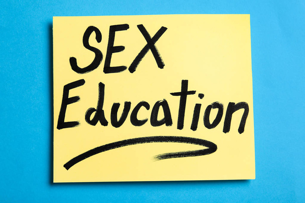 Zettel mit der Formulierung "Sexualerziehung" auf blauem Hintergrund, Ansicht von oben - Foto, Bild