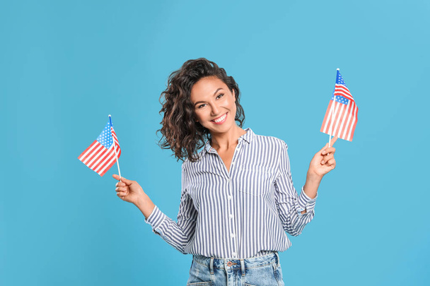happy young woman with American flags on blue background - Fotografie, Obrázek