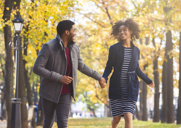 glückliches schwarzes Paar läuft über goldenen Park - Foto, Bild