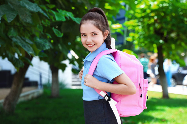Cute little girl in school uniform with pink backpack on street - Foto, afbeelding