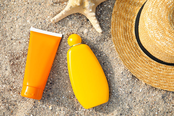 Flat lay composition with bottles of sun protection body cream on sand beach, space for design - Photo, image