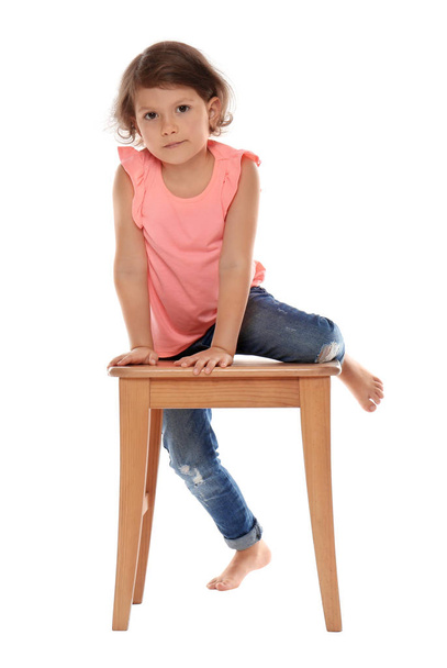 Little girl on stool against white background. Danger at home - Foto, Imagen