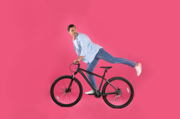 Handsome young man with modern bicycle on pink background - Foto, Bild