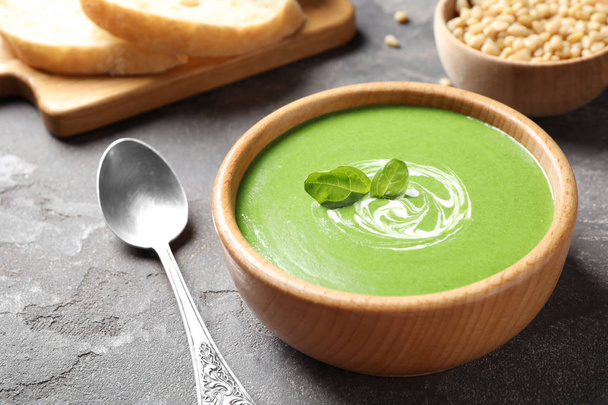 Bowl of healthy green soup with fresh spinach on grey table - Photo, Image