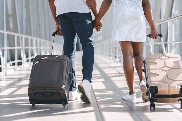 スーツケースを持って空港を歩くアフリカのカップル、クローズアップ - 写真・画像