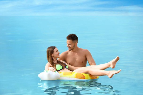 Happy woman in bikini floating on inflatable ring and her boyfriend in sea. Lovely couple - Zdjęcie, obraz