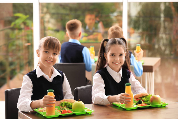 Happy girls at table with healthy food in school canteen - Foto, Imagen