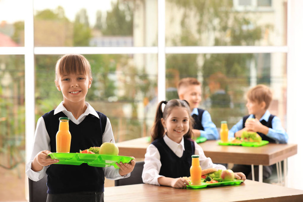 Happy girl holding tray with healthy food in school canteen - Foto, Imagen