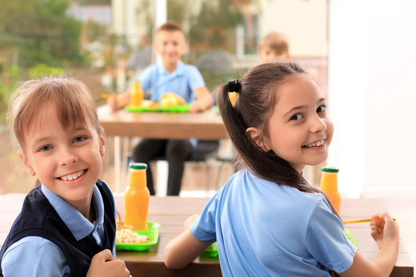 Szczęśliwy dziewcząt w tabela z zdrowy żywność w Szkoła stołteen - Zdjęcie, obraz