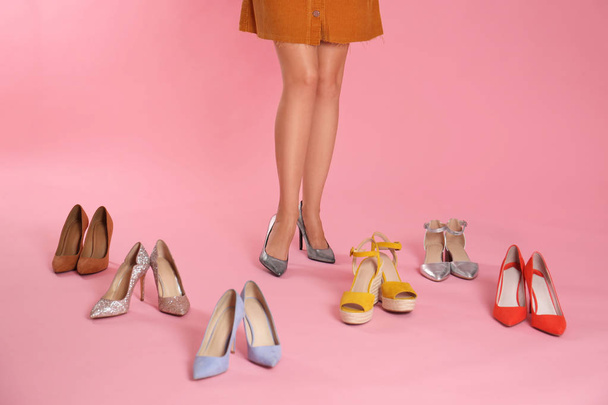 Woman trying on different high heel shoes on pink background, closeup - 写真・画像