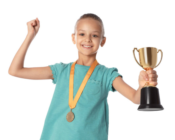Menina feliz com copo de ouro vencedor e medalha no fundo branco
 - Foto, Imagem