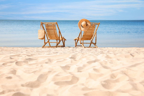 Wooden deck chairs on sandy beach near sea - Foto, Bild