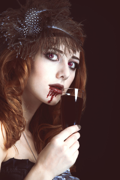 Redhead vampire woman with glass of blood. Photo in vintage styl - Foto, Imagen