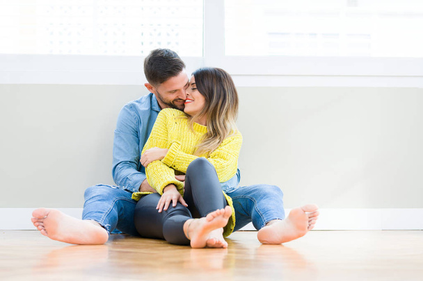 Beautiful young couple in love, kissing and hugging each other sitting on the floor at home - Photo, Image