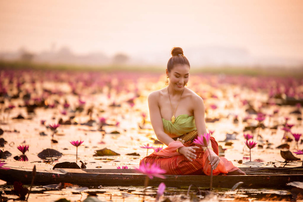 Woman In Traditional Clothing Holding Lotus While Sitting On Boat In Lake - Photo, Image