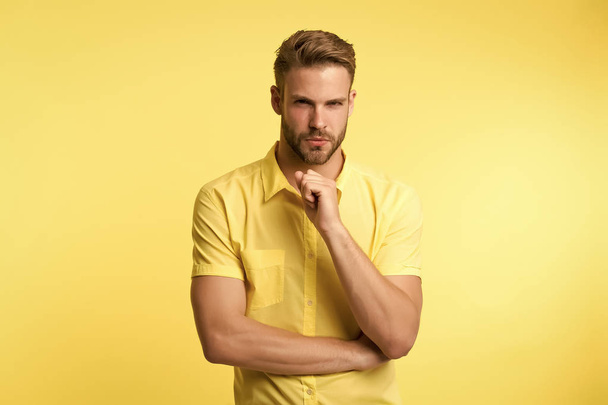 Asking himself. Handsome young man keeping hand on chin while stand yellow background. Existentialism concept. Hard question. Moral question difficulties. Listen to yourself. Question without answer - Foto, Bild