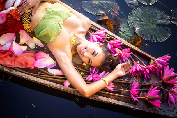 Top view Kobieta w tradycyjnej odzieży leżącej przez różowy Lotos w łodzi nad jeziorem - Zdjęcie, obraz