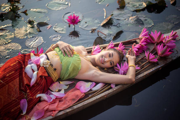 Top view Kobieta w tradycyjnej odzieży leżącej przez różowy Lotos w łodzi nad jeziorem - Zdjęcie, obraz