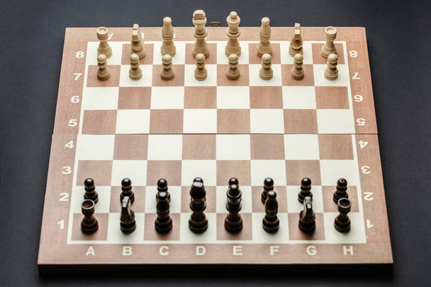 Schachfiguren auf einem Schachbrett, vor dunklem Hintergrund. - Foto, Bild