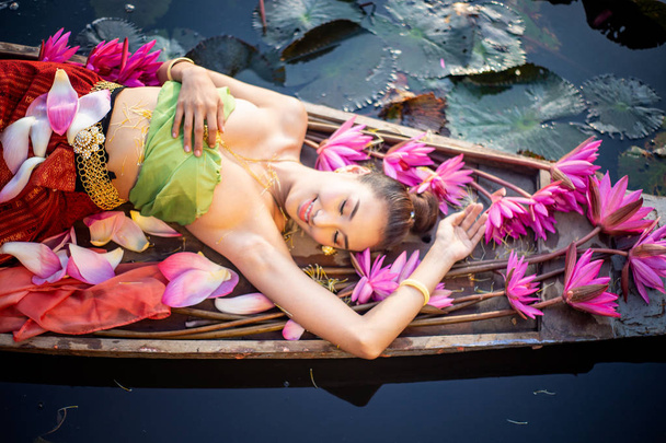 Kobieta w tradycyjnej odzieży leżącej w Pink Lotus w łodzi na jeziorze - Zdjęcie, obraz