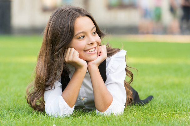 School break for rest. Adorable pupil. Girl kid laying lawn. Mental wellness. Girl school uniform enjoy relax. Importance of relaxation. Little schoolgirl. Relax at school yard. Kid relaxing outdoors - Photo, Image