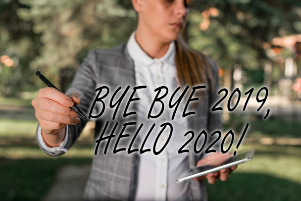 Szöveg jel mutatja bye bye 2019 Hello 2020. Konceptuális fotó búcsúzik tavaly, és üdvözölve egy jó egy kültéri háttérrel üzleti nő gazdaság lap tetején és toll. - Fotó, kép