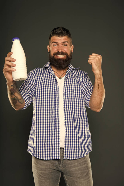 Dairy foods are good sources of protein and calcium. Bearded man holding bottle of dairy drink on grey background. Happy hipster enjoying dairy diet. Dairy menu - Fotoğraf, Görsel