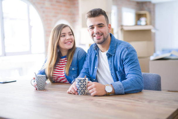 コーヒーを飲みながら休憩を取る若いカップルは、新しい家に引っ越すのに非常に幸せです - 写真・画像