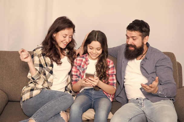 Child share news with mother and father. Little girl child use mobile phone. Happy family at home. Buy online. Child with childhood happiness. bearded man and woman with child. Family bonds - Foto, afbeelding