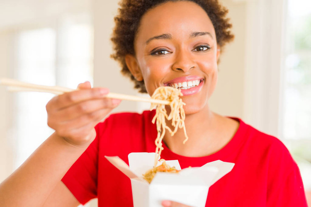 Beautiful young african american woman eating noodles using choopsticks - Photo, Image