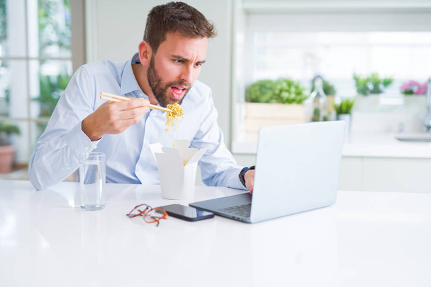 Business man eating take away asian noodles food while working u - Photo, image