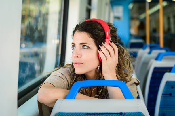 Beautiful young woman listening to music in a train. - Photo, image