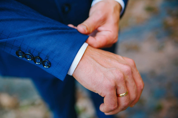 man straightens the cuff of a blue jacket with his hand - Foto, afbeelding