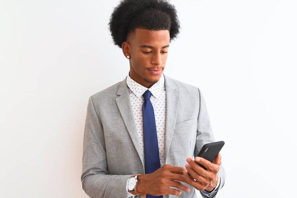 Young african american businessman using smartphone over isolated white background with a confident expression on smart face thinking serious - Foto, afbeelding