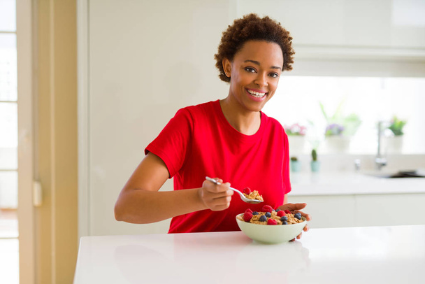 Młode piękne african american kobieta z włosów afro, jedzenie zdrowe płatki zbożowe i owoce jako zdrowe śniadanie - Zdjęcie, obraz
