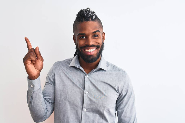 African american businessman with braids standing over isolated white background with a big smile on face, pointing with hand and finger to the side looking at the camera. - Foto, Imagen