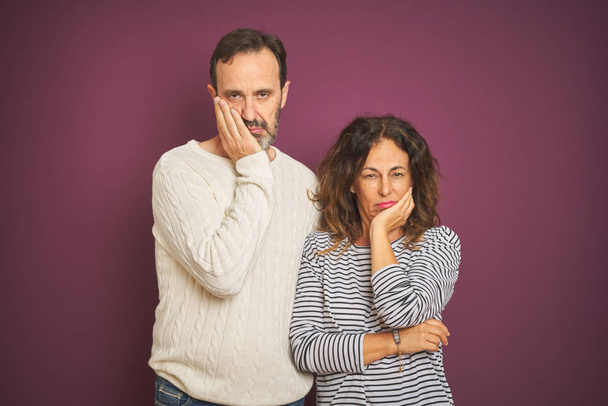 Beautiful middle age couple wearing winter sweater over isolated purple background thinking looking tired and bored with depression problems with crossed arms. - Foto, Imagen