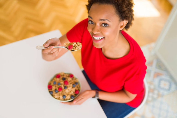 Young beautiful african american woman with afro hair eating hea - Zdjęcie, obraz