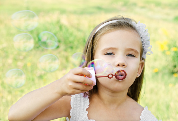 Cute little girl is blowing a soap bubbles - Foto, Imagen