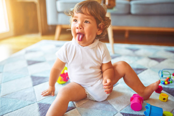 Красива дівчинка-малюк грає з іграшками на килимі
 - Фото, зображення