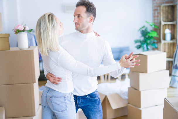 Young beautiful couple dancing at new home around cardboard boxes - Photo, image