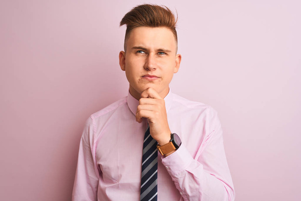 Young handsome businessman wearing shirt and tie standing over isolated pink background Thinking concentrated about doubt with finger on chin and looking up wondering - Photo, Image