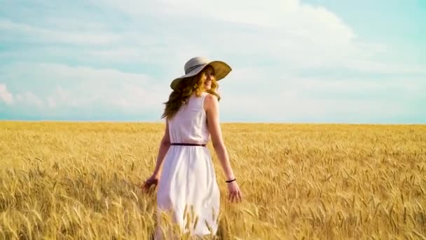 Pretty girl walking on wheat field in harvest season - Video, Çekim