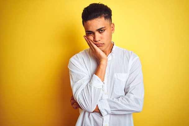 Fiatal brazil üzletember visel elegáns inget állt át elszigetelt sárga háttér gondolkodás látszó fáradt és unatkozott a depresszió problémák keresztbe fegyver. - Fotó, kép