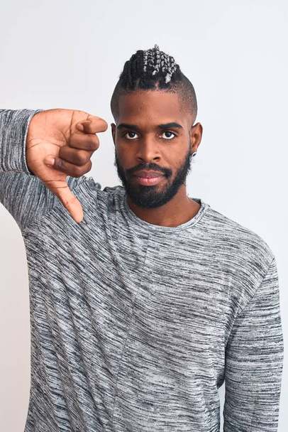 アフリカ系アメリカ人男性、怒った顔で孤立した白い背景の上に灰色のセーターを着て、親指を下にして嫌いを示す否定的なサイン、拒絶概念 - 写真・画像