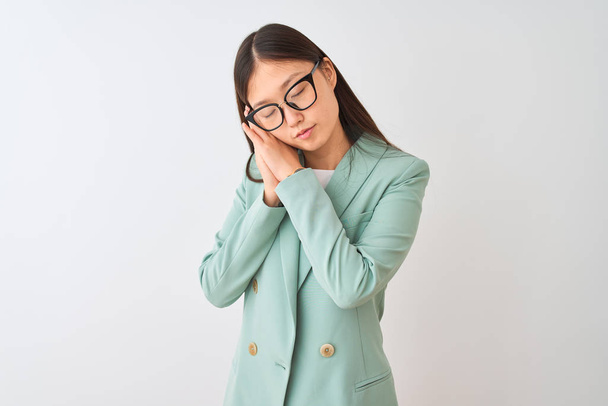 Chinese businesswoman wearing elegant jacket and glasses over isolated white background sleeping tired dreaming and posing with hands together while smiling with closed eyes. - Zdjęcie, obraz