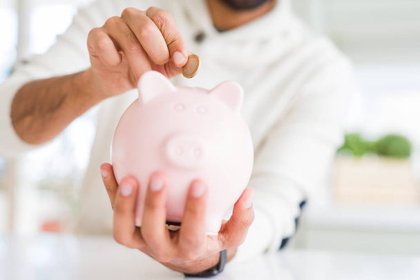 Man putting a coin inside of piggy bank saving for investment - Photo, Image