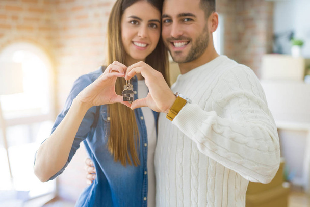 Casal jovem se mudando para uma nova casa, abraçando no amor mostrando chaves
  - Foto, Imagem