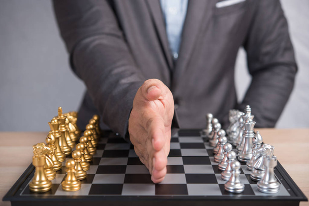бізнесмен поклав руку між золотою і срібною шаховою командою на бою
 - Фото, зображення